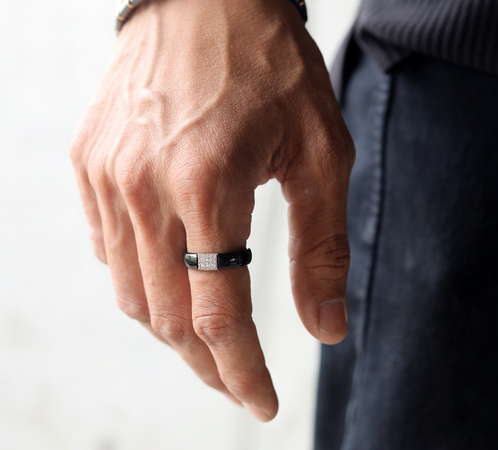 Hand wearing a black ring on a white background
